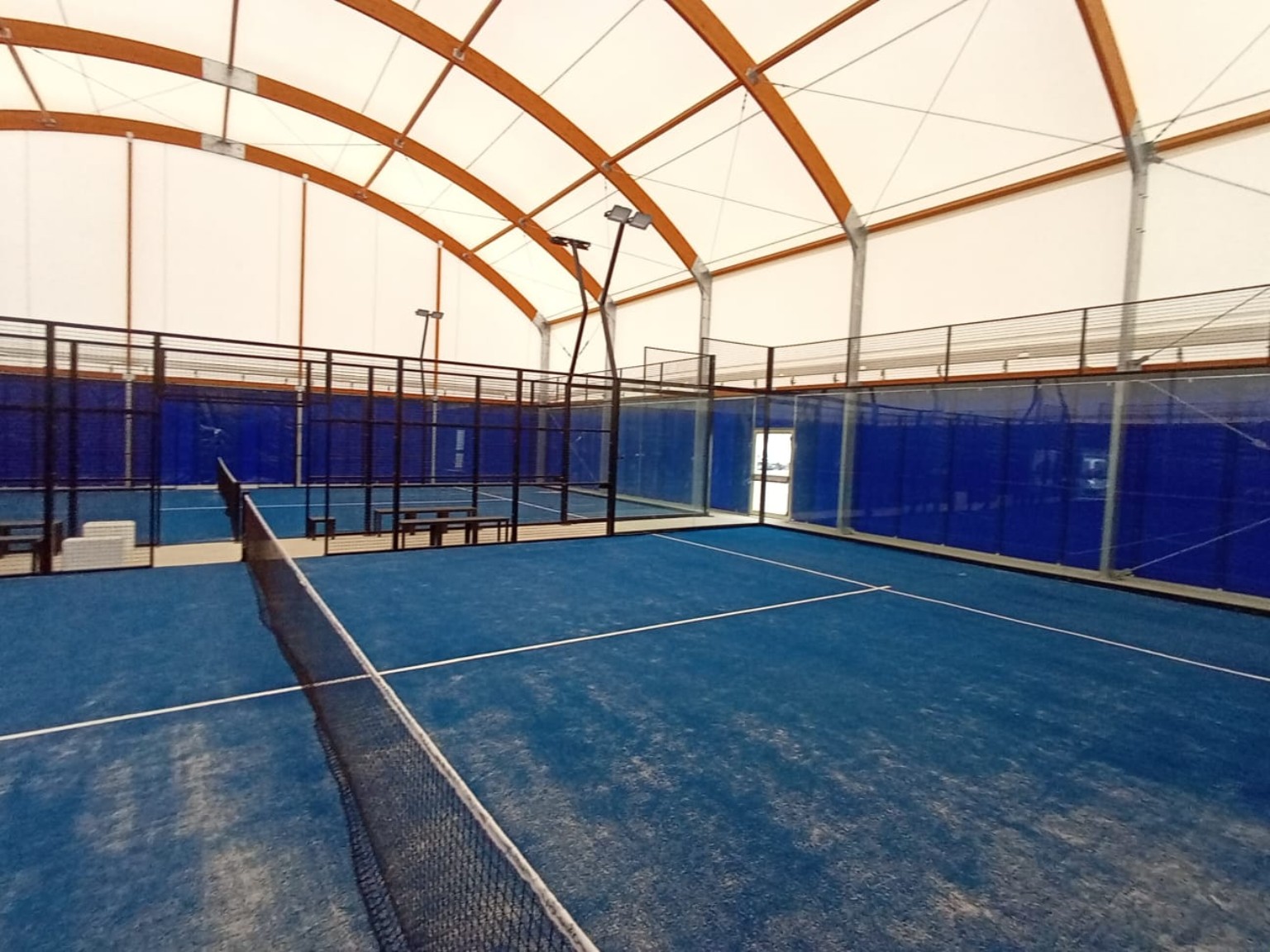Campo da padel coperto con archi in legno e pilastri in acciaio